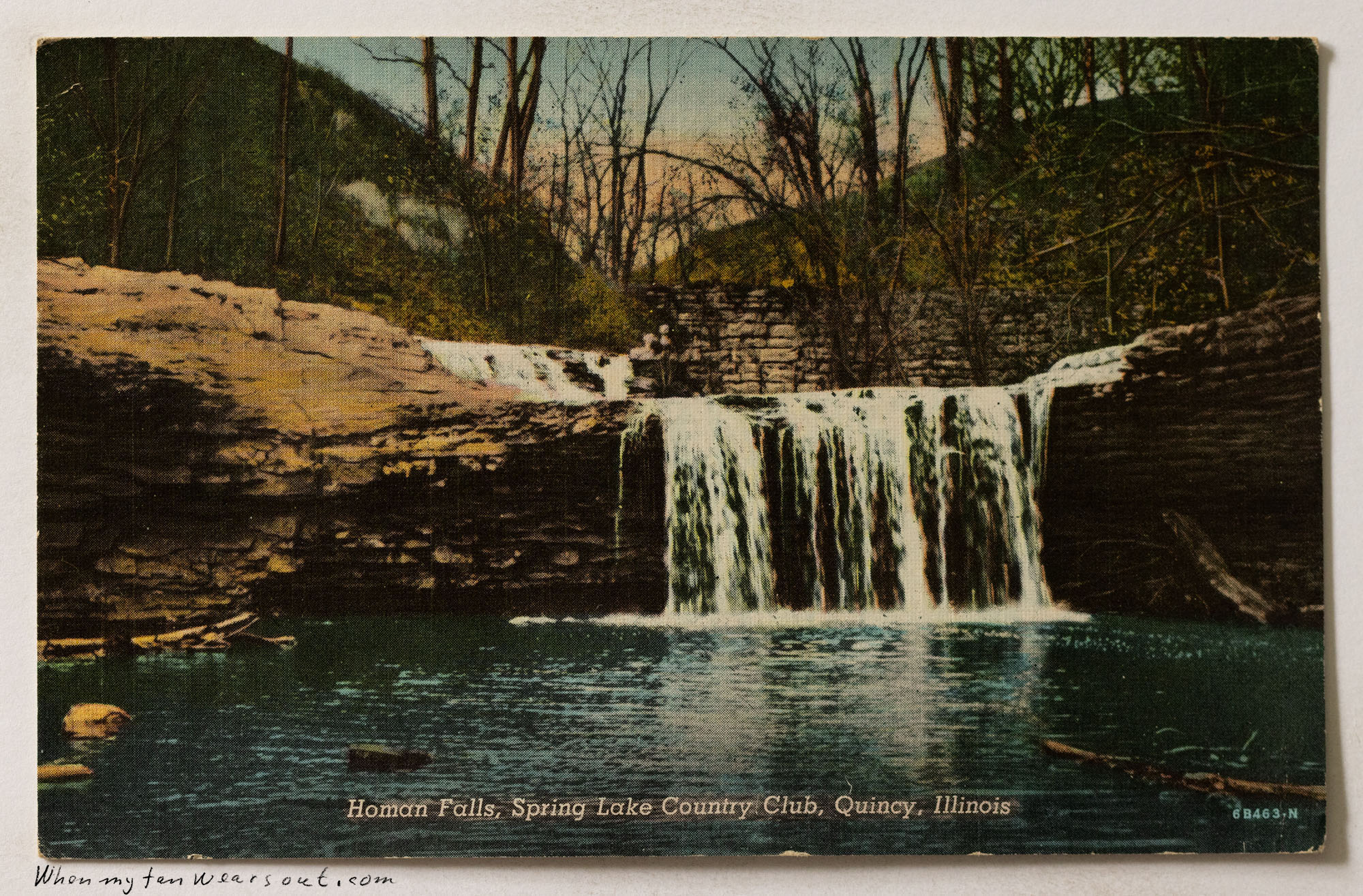 Front of postcard #1077: A linen-textured color illustration of Homan Falls, showing a wide waterfall cascading over a rocky ledge into a pool. T