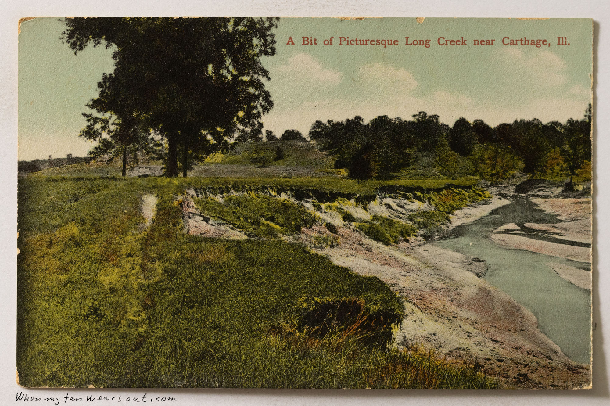 Front of postcard #1079: Hand-colored landscape view of Long Creek near Carthage, Illinois. The image shows a wide, shallow creek bed with muddy 